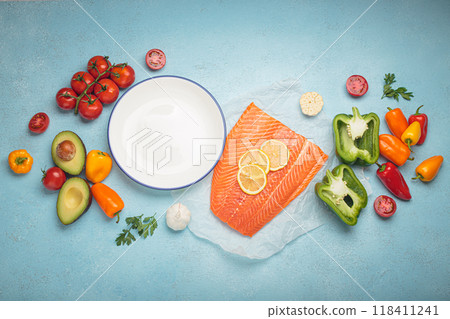Fresh salmon with vegetables and empty plate lying on blue background 118411241