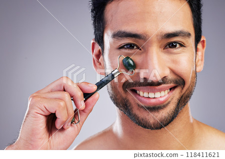 Happy man, portrait or face massage with roller or product for healthy skincare on studio background. Cheek, crystal stone treatment or male model with facial dermatology cosmetic for beauty glow 118411621