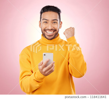 Winner portrait, man and phone for success, yes and celebration of news, social media or gaming results. Excited, mobile games and person with notification or website bonus on studio, pink background 118411641