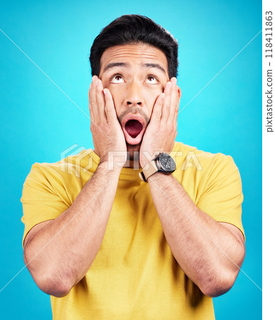Man, wow and shocked at surprise or announcement in studio with hands on face and mouth open. Male model person on a blue background while thinking of gossip, sale or promotion with comic emoji Man, wow and shocked at surprise or announcement in studio with hands on face and mouth open. Male model person on a blue background while thinking of gossip, sale or promotion with comic emoji 118411863