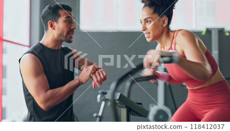Fitness, training on an exercise bike and a woman with her coach in the gym to time her speed on a sports watch. Exercise, motivation and a personal trainer with a young athlete for workout support 118412037