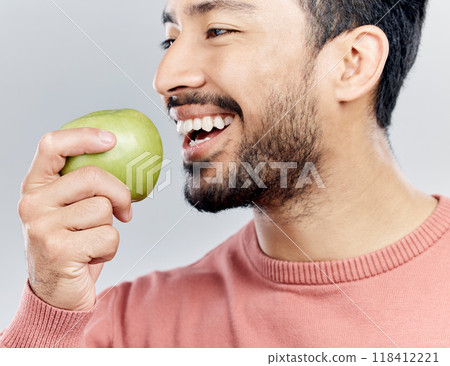 Enjoying, happy and an Asian man eating an apple isolated on a white background in a studio. Smile, food and a Chinese guy taking a bite from a fruit for nutrition, diet or hungry on a backdrop 118412221
