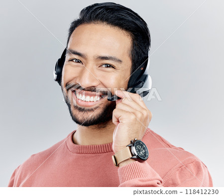Asian man, portrait smile and headphones with mic for call center or online customer service against a white studio background. Happy male consultant with headset smiling for wireless communication 118412230