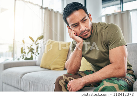 PTSD, anger or depression with a military man in uniform sitting on a sofa in the living room of his home. Mental health, stress or psychology with a male soldier thinking about a war memory 118412378