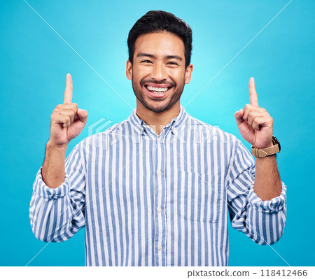 Point, happy and portrait of Asian man on blue background for news, information and announcement. Advertising, studio mockup and face of excited male pointing for copy space, promo and showing sign 118412466