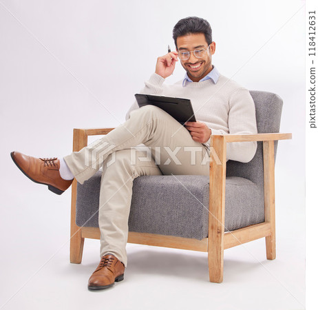 Chair, clipboard and therapist man isolated on a white background reading therapy notes, checklist and review. Asian professional person or psychologist relax on armchair with career folder in studio 118412631