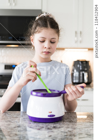 With focused attention, this budding culinary artist dips pretzels into a pot of melted chocolate, creating sweet delights in the warmth of a well-lit home kitchen. With focused attention, this budding culinary artist dips pretzels into a pot of melted chocolate, creating sweet delights in the warmth of a well-lit home kitchen. 118412904