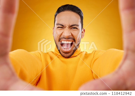 Screaming, portrait and selfie of angry man in studio isolated on a yellow background. Face, shouting and Asian person taking profile picture for memory in anger, frustrated or stress for problem 118412942