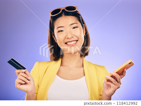 Phone, credit card and portrait of a woman in a studio for online shopping with a positive mindset. Happy, smile and Asian female model with internet banking for paying bills by a purple background. 118412992