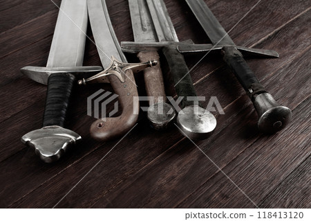 Swords and sabre on wooden background. 118413120