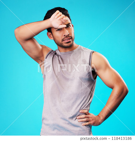 Portrait, fitness and Asian man tired after exercise in studio isolated on a blue background. Face, serious and athlete with fatigue, wipe sweat and workout for sports, healthy body and wellness 118413186