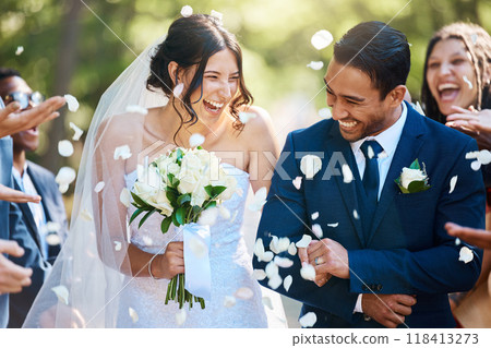 Love, wedding and couple walking with petals and guests throwing in celebration of romance. Happy, smile and young bride with bouquet and groom with crowd celebrating at the outdoor marriage ceremony Love, wedding and couple walking with petals and guests throwing in celebration of romance. Happy, smile and young bride with bouquet and groom with crowd celebrating at the outdoor marriage ceremony 118413273