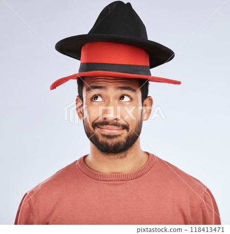 Confused, hats and young man in a studio with a thinking, idea or contemplating face expression. Pensive, thoughtful and Indian male person with fun head accessories isolated by a white background. 118413471