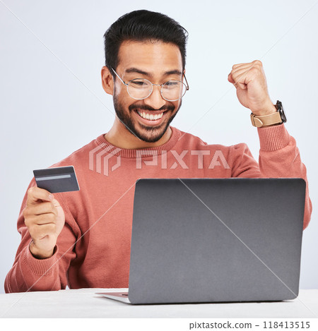 Laptop, credit card and man excited for online shopping, e commerce and payment in studio. Asian male person with technology and hand to celebrate savings win, promotion or sale on a fintech website Laptop, credit card and man excited for online shopping, e commerce and payment in studio. Asian male person with technology and hand to celebrate savings win, promotion or sale on a fintech website 118413515