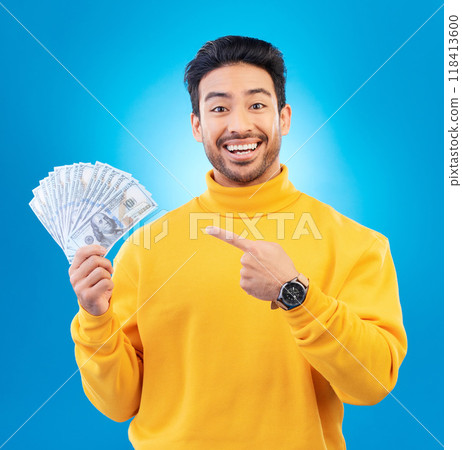 Money, studio portrait and happy man point at dollar bills, competition reward or bonus salary prize. Savings pay, cash winner and excited person show income, success or wealth on blue background Money, studio portrait and happy man point at dollar bills, competition reward or bonus salary prize. Savings pay, cash winner and excited person show income, success or wealth on blue background 118413600