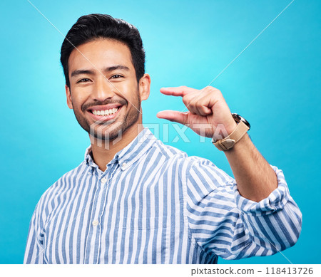 Small, hand and gesture of a man portrait with a smile in studio showing a tiny measurement. Isolated, blue background and Asian model with happiness, positive opinion and hands show of pinch size Small, hand and gesture of a man portrait with a smile in studio showing a tiny measurement. Isolated, blue background and Asian model with happiness, positive opinion and hands show of pinch size 118413726