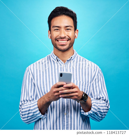 Happy, portrait and a man with a phone for communication isolated on a blue background in a studio. Smile, social media update and a person typing on a mobile for app, notification reply and message Happy, portrait and a man with a phone for communication isolated on a blue background in a studio. Smile, social media update and a person typing on a mobile for app, notification reply and message 118413727