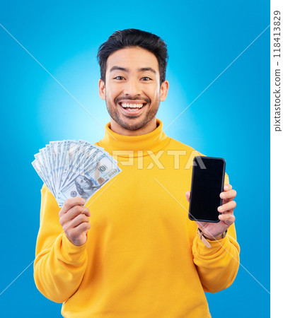 Money, online and prize with portrait and asian man in blue background with for gambling or profit. Cash, winning and guy with fintech mobile app for competition or celebration with dollar in studio. 118413829