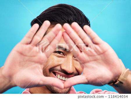 Frame, hands and portrait of happy Asian man on blue background with smile, confidence and happiness. Perspective, shape and face of male person in studio for photography, profile picture and vision Frame, hands and portrait of happy Asian man on blue background with smile, confidence and happiness. Perspective, shape and face of male person in studio for photography, profile picture and vision 118414034