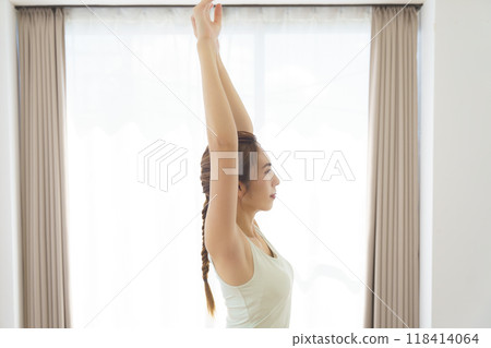 A young woman taking an online yoga class at home 118414064