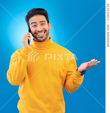 Happy, conversation and portrait of an Asian man on a phone call for communication and networking. Smile, technology and a person speaking on a mobile isolated on a blue background in a studio 118414250