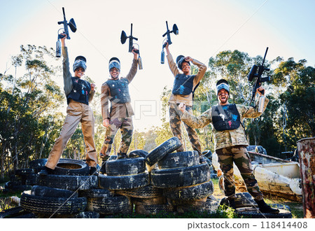 Team, paintball and portrait in celebration for winning, victory or achievement standing on tires together in nature. Group of people enjoying win, success or teamwork with guns in the air for sports 118414408