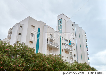 Luxurious High-Rise Apartment Building Surrounded by Tropical Palm Trees on Hot Sunny Summer Day Perfect Vacation Destination, Modern Multi-Story Residential Complex Amidst Lush Palm Trees Cloudless Luxurious High-Rise Apartment Building Surrounded by Tropical Palm Trees on Hot Sunny Summer Day Perfect Vacation Destination, Modern Multi-Story Residential Complex Amidst Lush Palm Trees Cloudless 118414806