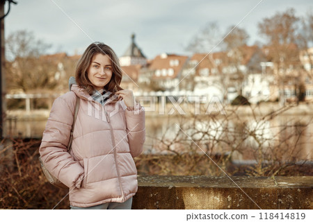 Young beautiful pretty tourist girl in warm hat and coat with backpack walking at cold autumn in Europe city enjoying her travel in Bietigheim-Bissingen, Deutschland. Outdoor portrait of young tourist 118414819