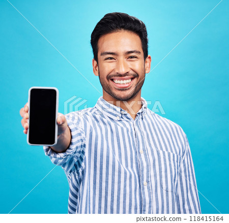 Phone screen, mockup and portrait of man isolated on blue background for mobile app or advertising space. Happy face of asian person with cellphone mock up for website, contact or ux design in studio 118415164