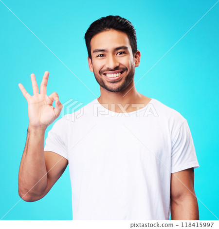 Happy, perfect gesture and portrait of a man in a studio with an agreement sign or expression. Happiness, smile and young Indian male model with an approval hand emoji isolated by a blue background. Happy, perfect gesture and portrait of a man in a studio with an agreement sign or expression. Happiness, smile and young Indian male model with an approval hand emoji isolated by a blue background. 118415997