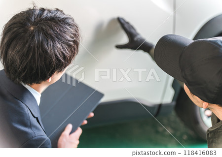 A male mechanic and a salesman in a suit checking scratches and dents on a car A male mechanic and a salesman in a suit checking scratches and dents on a car 118416083