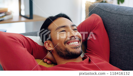 Lying, face and man with smile on a sofa in living room after work for peace, freedom and happy thinking. Asian, person and relax on couch in lounge of home on a day off and weekend with happiness 118416132
