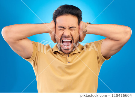 Man covering his ears while screaming in a studio for angry, upset or mad argument expression. Crazy, shout and young male person with an open mouth for loud voice gesture isolated by blue background Man covering his ears while screaming in a studio for angry, upset or mad argument expression. Crazy, shout and young male person with an open mouth for loud voice gesture isolated by blue background 118416604