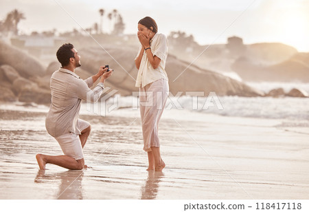 Couple at beach, surprise proposal and engagement with love and commitment with ocean and people outdoor. Travel, seaside and man propose marriage to woman, wow reaction and happiness with care Couple at beach, surprise proposal and engagement with love and commitment with ocean and people outdoor. Travel, seaside and man propose marriage to woman, wow reaction and happiness with care 118417118