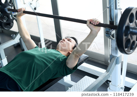Young Asian man doing bench press in gym Young Asian man doing bench press in gym 118417239