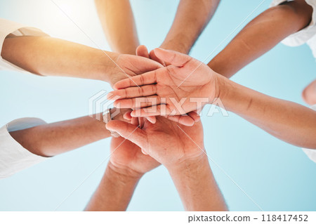 Circle, low angle and team with hands together for collaboration, unity or support by a blue sky. Teamwork, diversity and group of people in an outdoor huddle for motivation, solidarity or community. Circle, low angle and team with hands together for collaboration, unity or support by a blue sky. Teamwork, diversity and group of people in an outdoor huddle for motivation, solidarity or community. 118417452