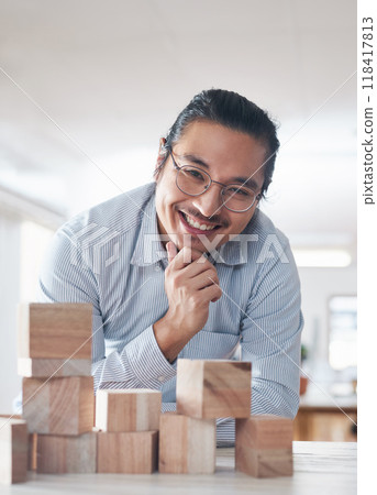 Portrait of businessman with smile, growth and blocks, thinking challenge game and design balance. Engineering, architecture and happiness, asian designer with building block problem solving games. 118417813