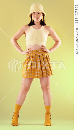 Fashion, gen z and Asian woman in yellow, beauty and streetwear with style on studio background. Trendy, bright aesthetic with model and funky designer brand clothes, stylish female in portrait 118417861