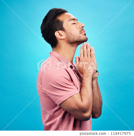 Man is praying, religion and faith with worship to God, belief and spirituality isolated on blue background. Male person in prayer, Christian and gratitude with mindfulness and peace in studio 118417975