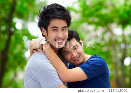 Asian men, gay couple and hug by trees, portrait and woods with love, care and bonding in summer sunshine. Happy Japanese man, romance and relax together in forrest with lgbtq, nature and holiday 118418091
