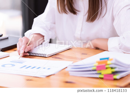 Hand of a businesswoman working with papers and documents at a desk in the office. Hand of a businesswoman working with papers and documents at a desk in the office. 118418133