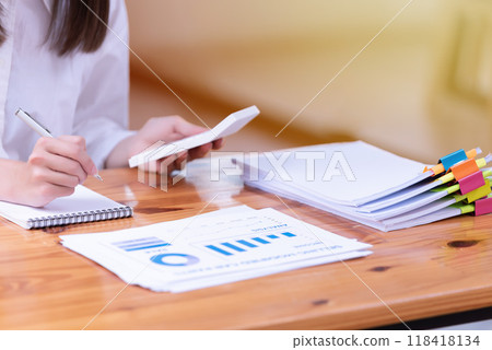 Hand of a businesswoman working with a calculator and documents at a desk in the office. Hand of a businesswoman working with a calculator and documents at a desk in the office. 118418134