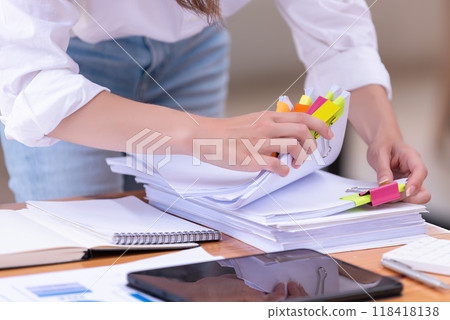 Hand of a businesswoman working for searching in Stacks of paper documents on wooden desks at the workplace Hand of a businesswoman working for searching in Stacks of paper documents on wooden desks at the workplace 118418138