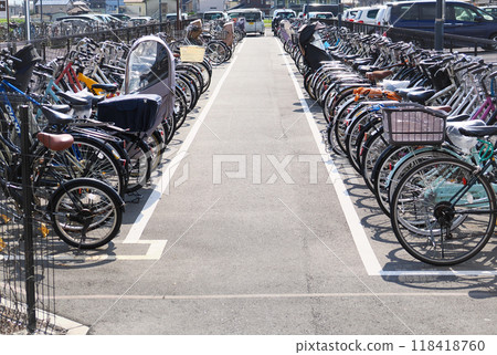 A bicycle parking lot in front of the station on a sunny day with many bicycles lined up A bicycle parking lot in front of the station on a sunny day with many bicycles lined up 118418760
