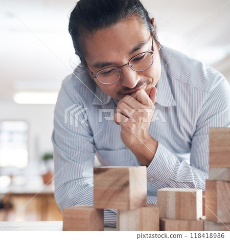 Thinking, ideas and Asian man in office with building blocks, strategy game and design balance with innovation. Engineering, architecture and designer with idea, wood block game and problem solving. 118418986