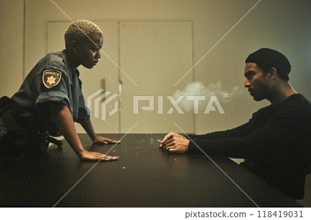 Man, smoking and detective talking in interrogation room with criminal, suspect or interview with a gangster. Police officer, questioning and statement of truth on crime and person with cigarette 118419031