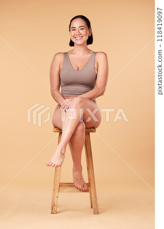 Portrait, beauty and an asian woman on a chair in studio on a beige background for natural body positivity. Model, underwear and an attractive young female sitting on a stool with confidence Portrait, beauty and an asian woman on a chair in studio on a beige background for natural body positivity. Model, underwear and an attractive young female sitting on a stool with confidence 118419097