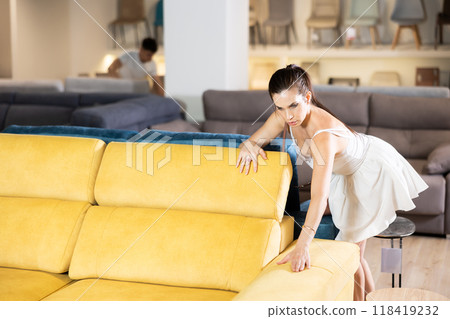 Young woman choosing convenient sofa in furniture shop 118419232