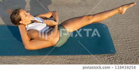 Sportive girl practicing complex pose of yoga on seashore Sportive girl practicing complex pose of yoga on seashore 118419258