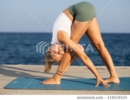 Yoga pose called uttanasana performed by a girl on seashore 118419324